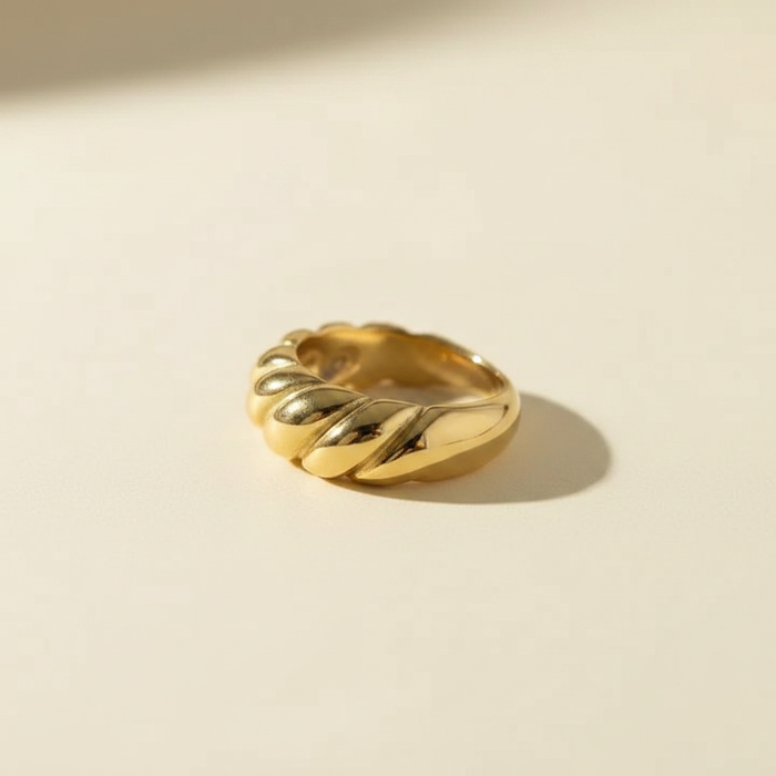 Side profile studio product image of an 18K gold PVD croissant twisted dome ring shown alone