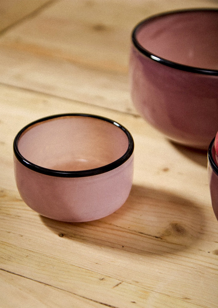 Glass bowls in mauve hue with black rim.