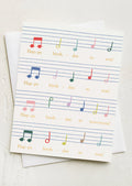 A card with rainbow colored sheet music to the tune of Happy Birthday song.