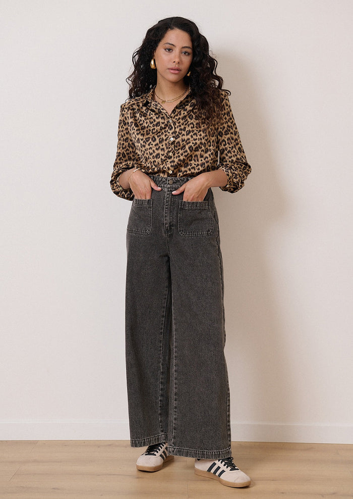 A woman wearing a long sleeve leopard print collared shirt.