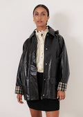 A woman wearing a patent jacket in black with plaid lining.