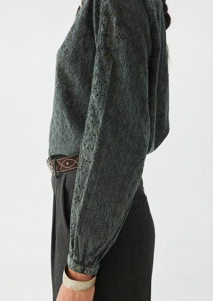 A woman wearing a dark grey cotton eyelet blouse.