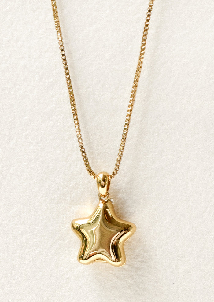 A gold necklace with a puffy star locket pendant.
