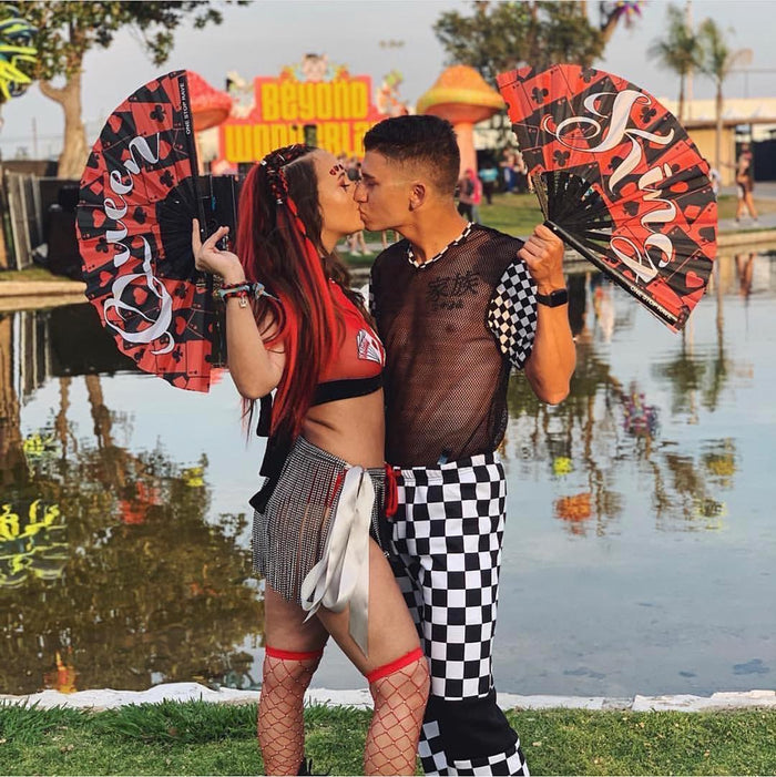 Couple holding King and Queen of Hearts hand fans at Beyond Wonderland festival.