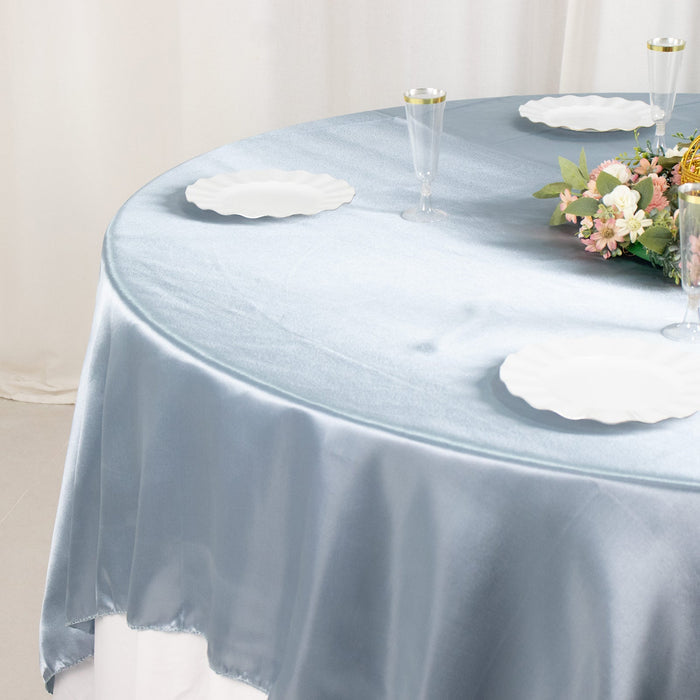 Blue satin tablecloth with white plates and floral centerpiece.